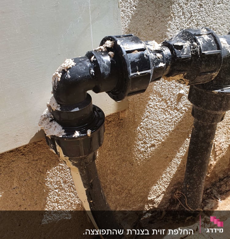 צינור פלסטיק שחור עם חיבורים על קיר חיצוני